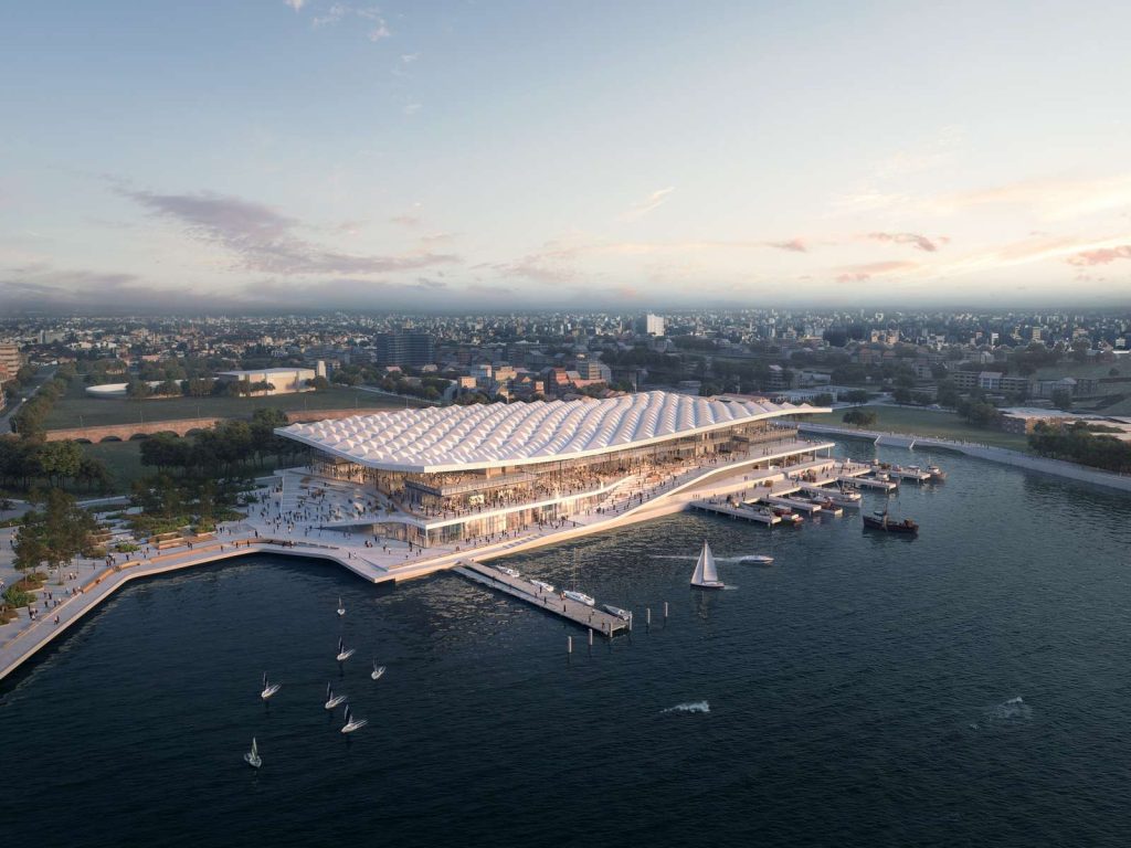 Exterior view of the New Sydney Fish Market at Blackwattle Bay, showcasing the undulating roof canopy and public waterfront spaces.
