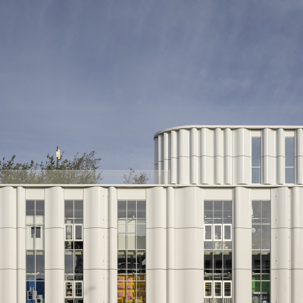 White, flowing curtain-inspired facade of IKEA Copenhagen integrated with rooftop greenery.